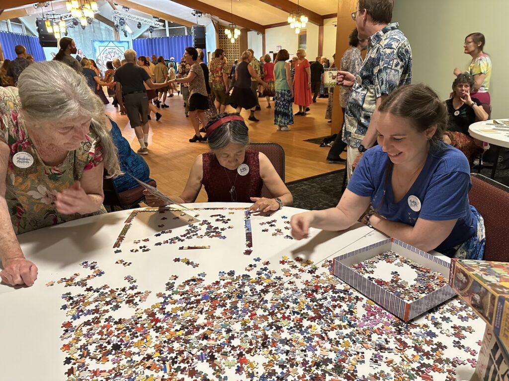 People smiling and working on a jigsaw puzzle at Hey Days 2025.