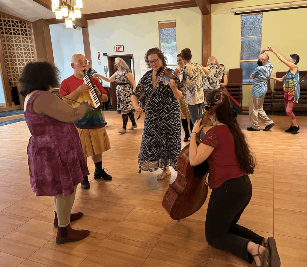 Staff musicians on the floor with waltzers dancing around them at Hey Days 2025.