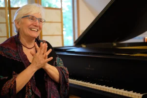 Jacqueline Schwab smiling next to piano
